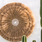 Runde Wanddeko mit Kauri Muscheln und Raffia